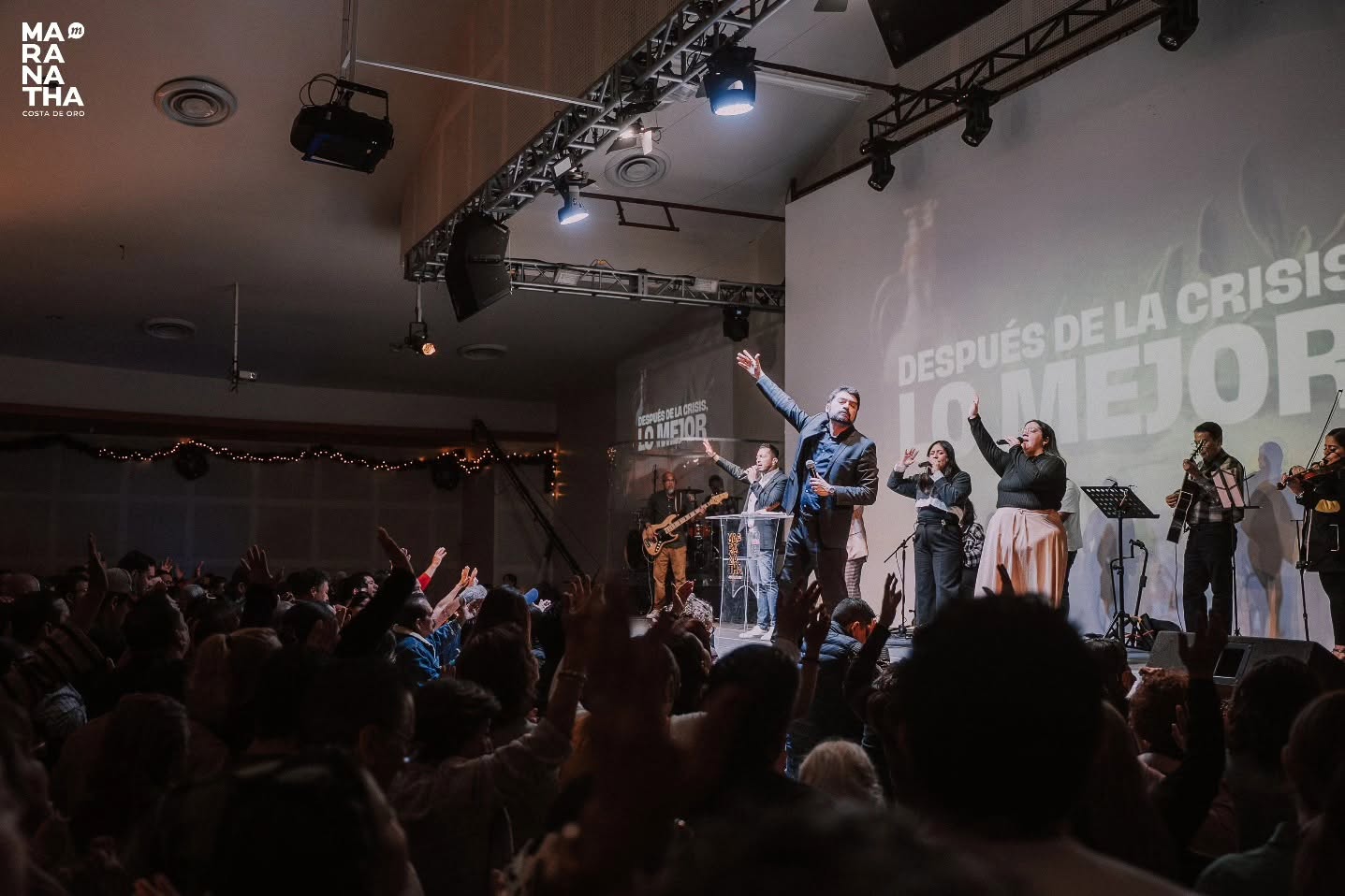 Congregación adorando con las manos levantadas durante un culto.
